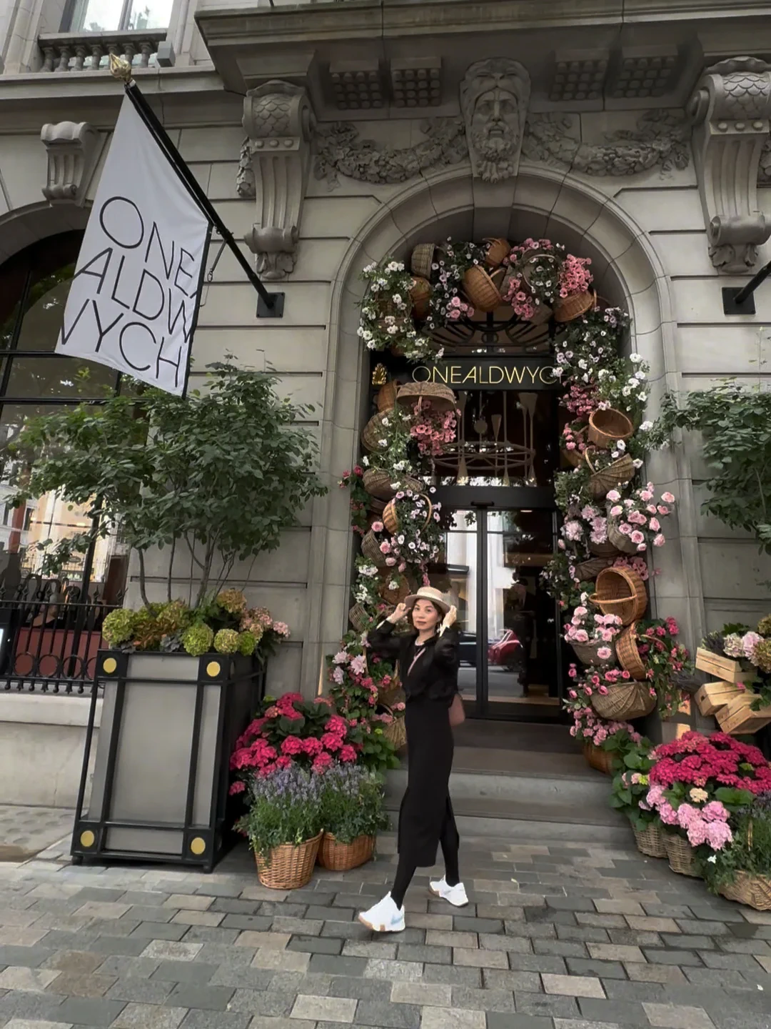 Alicia Dai in a black dress outside a flower-filled London storefront